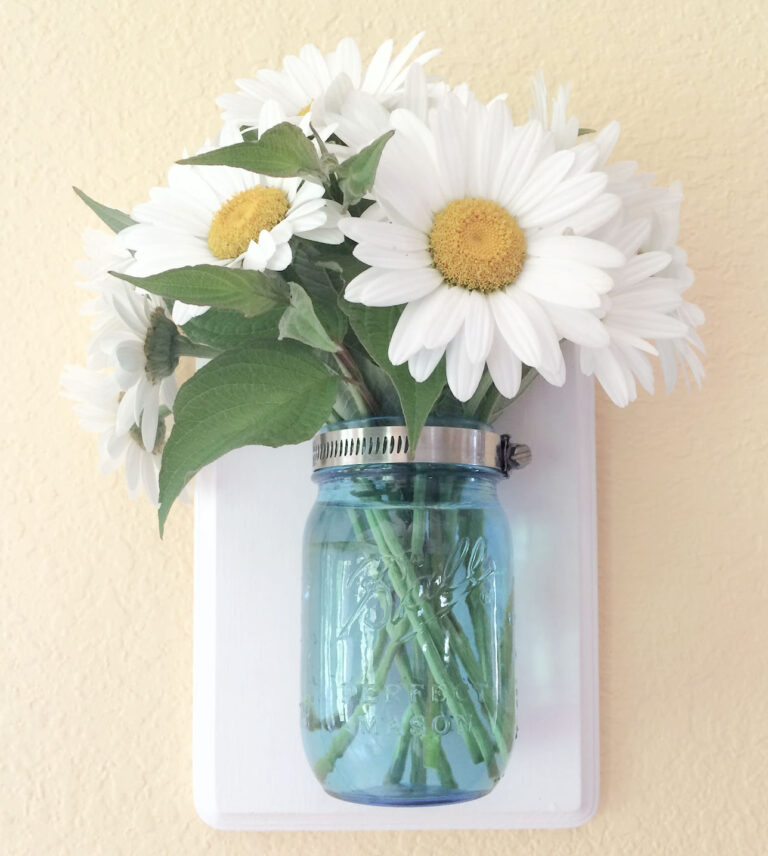 beautiful way to have flowers in a vase but not on your counter! Daisies in a wall mounted mason jar.
